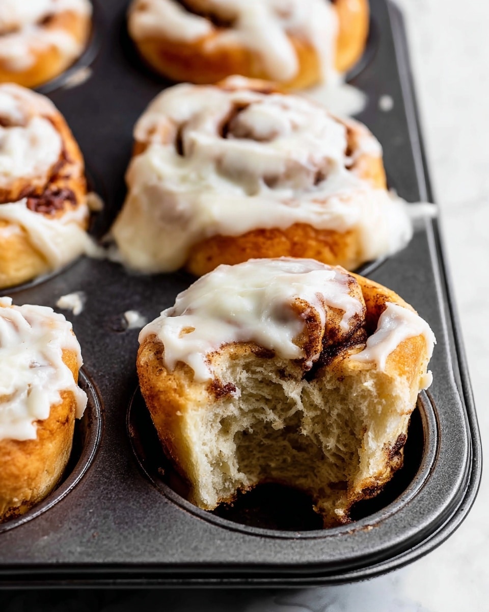 A black muffin tray with nine cinnamon rolls is shown from above on a white marbled surface. On the left side, the cinnamon rolls are raw, with a pale dough base and swirled brown cinnamon sugar filling visible in each roll, each one layered in spirals about three to four layers thick. On the right side, the same rolls are baked, with a light golden-brown crust on the dough and darker brown cinnamon filling lines making the spiral pattern clear. The rolls have puffed up slightly, with a soft texture and some deeper brown spots where the cinnamon sugar caramelized. The tray edges show some light reflections, enhancing the contrast between the dark black tray and the rolls. photo taken with an iphone --ar 4:5 --v 7